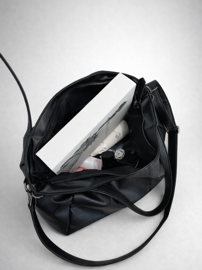 Black leather handbag with a white interior on a light gray background