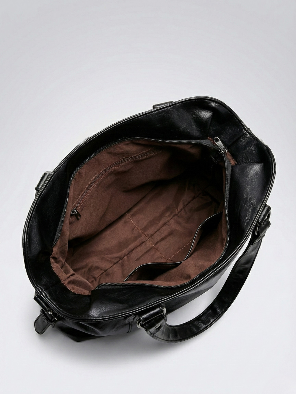 Black leather bag with open interior on a light gray background