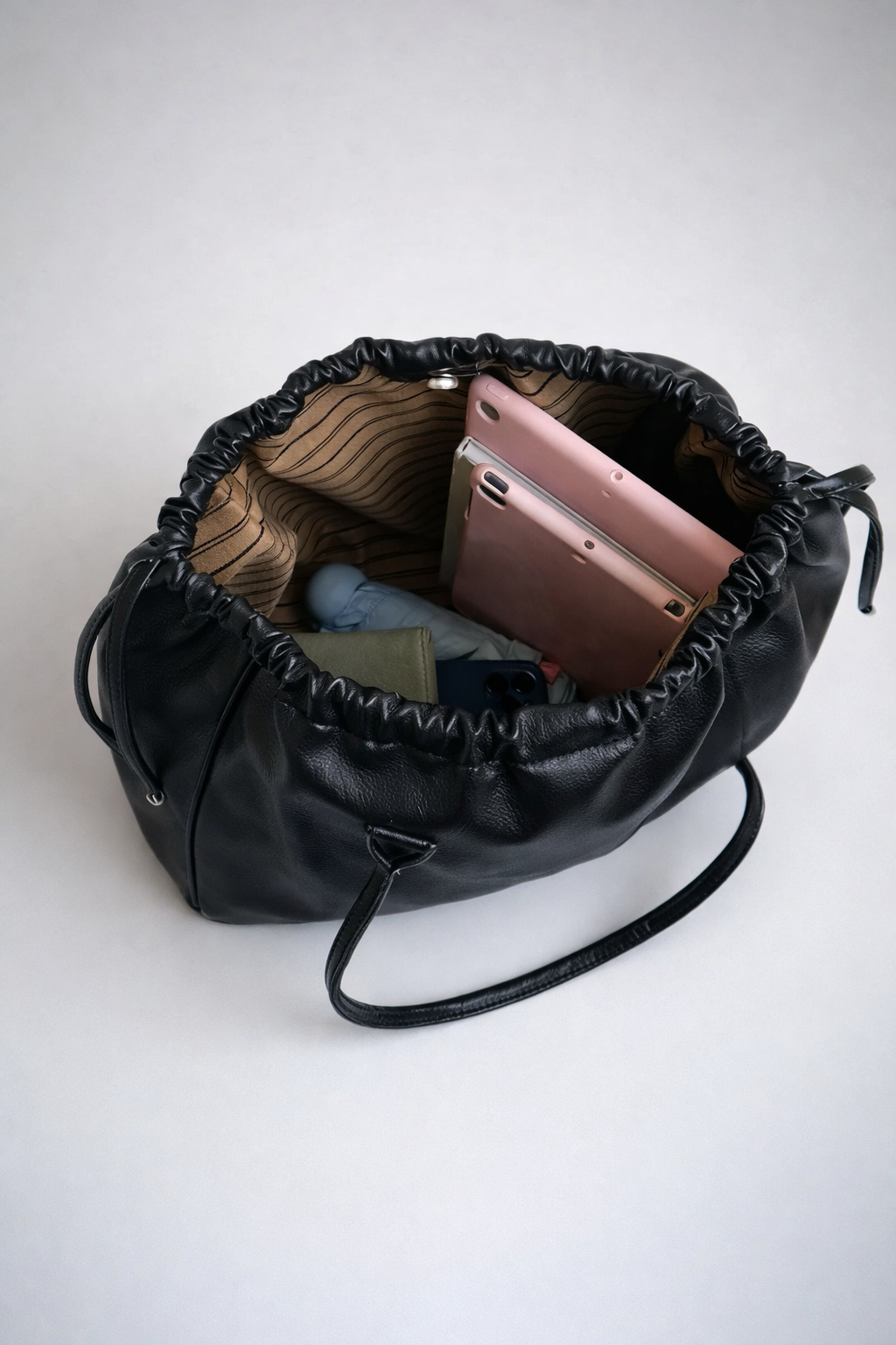 Black drawstring bag with phone and other items on a white background