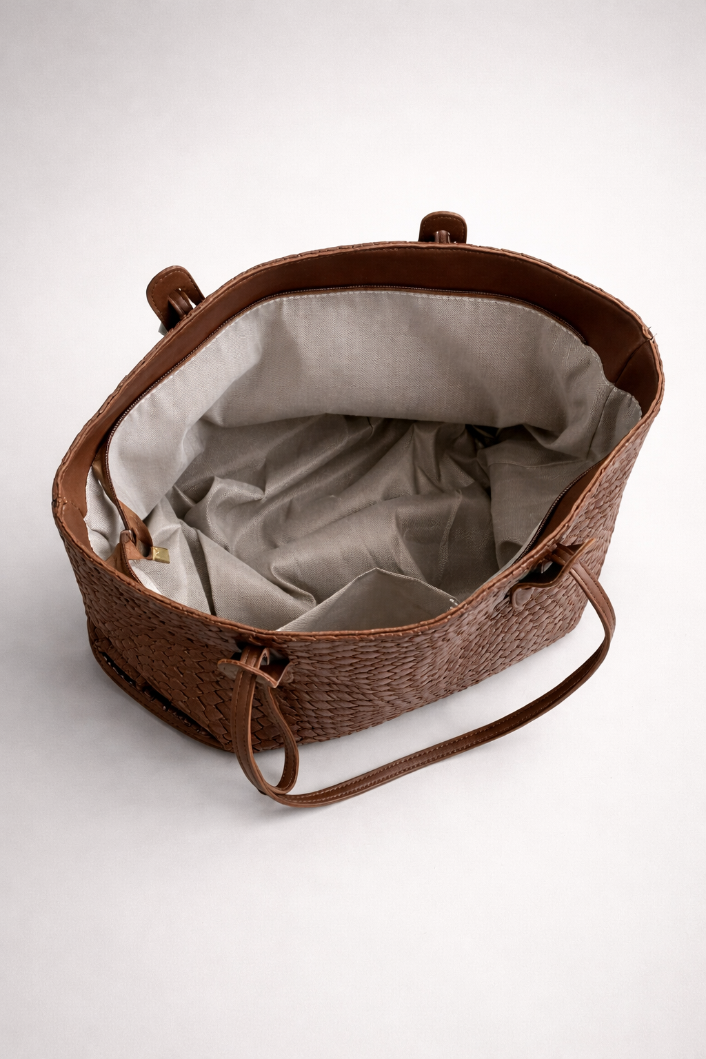 Brown woven bag with a beige interior on a white background