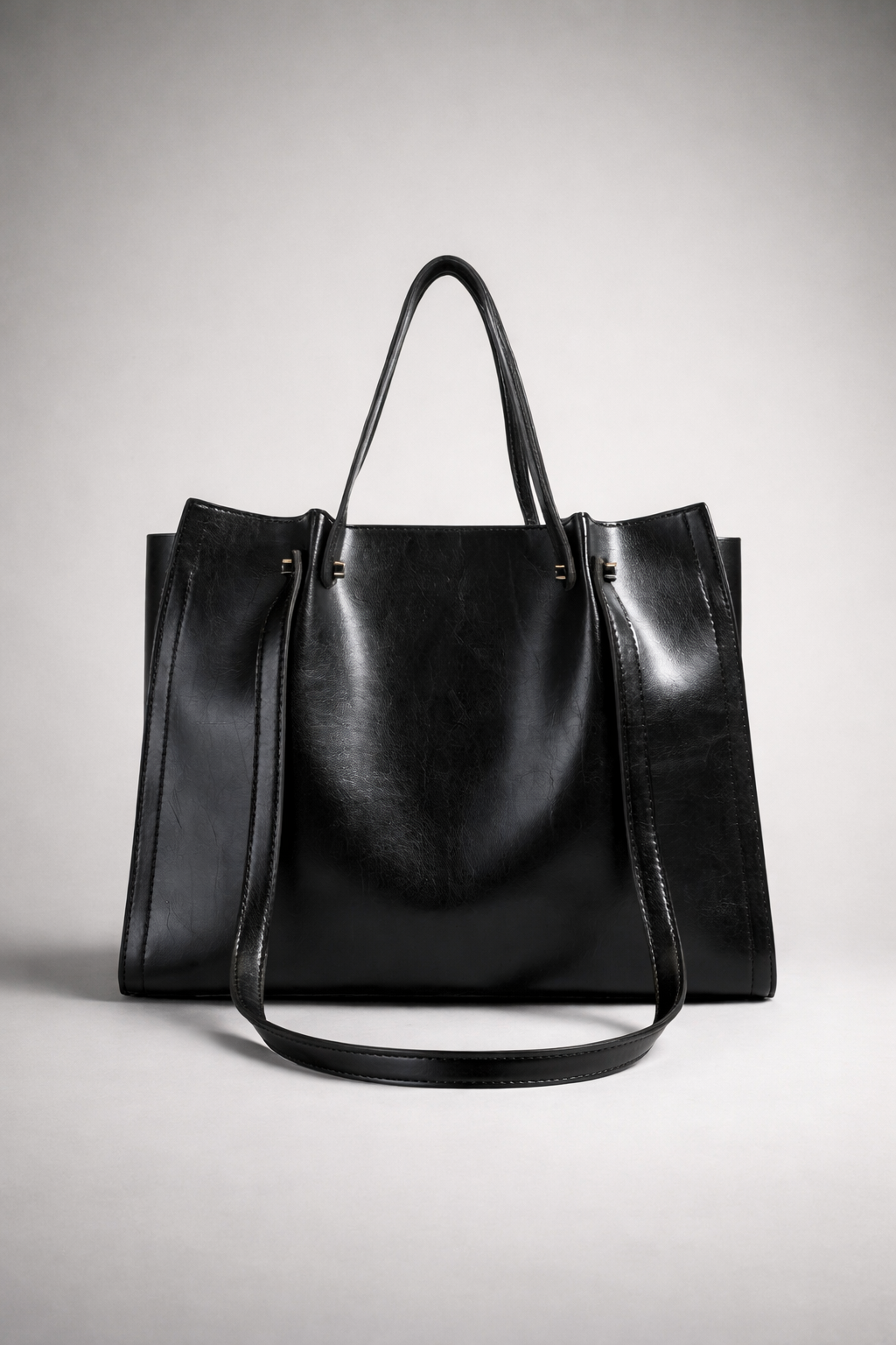 Black leather tote bag on a light gray background