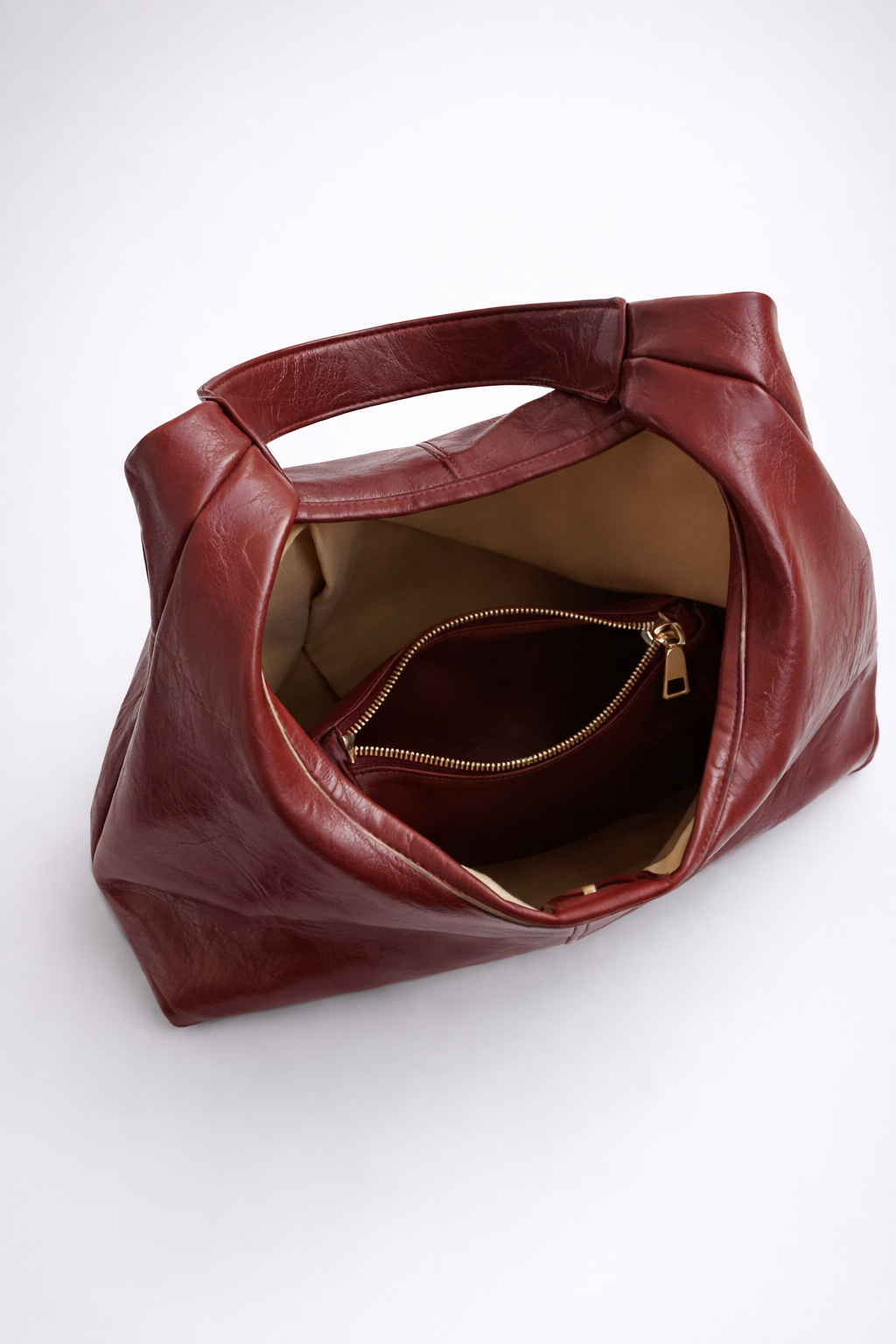 Brown leather handbag with a gold zipper on a white background