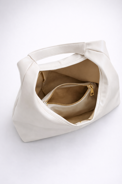 White handbag with a gold zipper on a white background