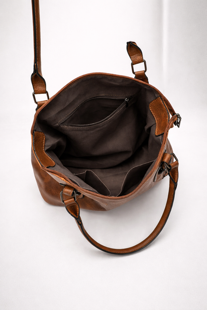 Brown leather bag with a shoulder strap on a white background