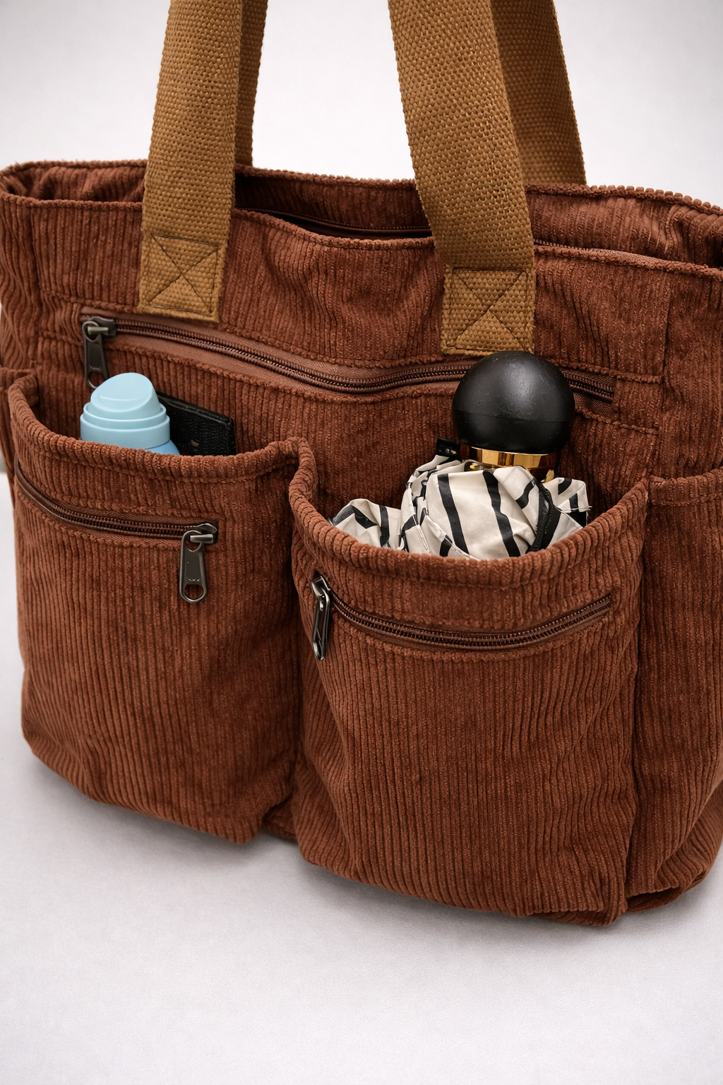 Brown corduroy tote bag with multiple pockets on a white background